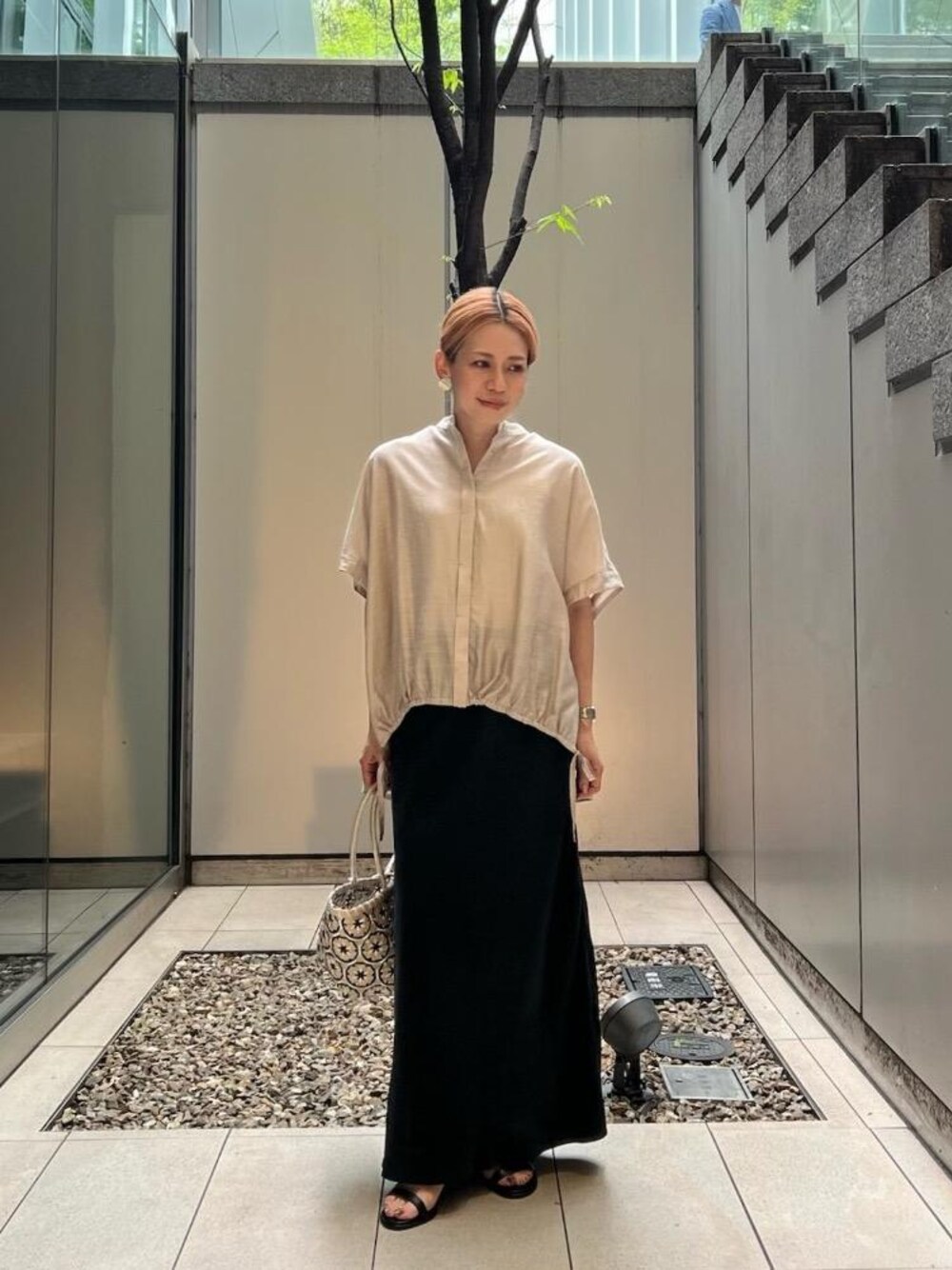 ベージュ系のトートバッグ、ベージュ系のシャツ/ブラウス、ブラック系のスカートを着用したレディースの春コーディネートの1枚目の写真