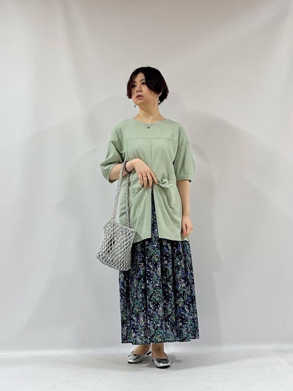 シルバー系のショルダーバッグ、ブルー系のスカート、グリーン系のTシャツ/カットソーを着用したレディースの夏コーディネートの1枚目の写真