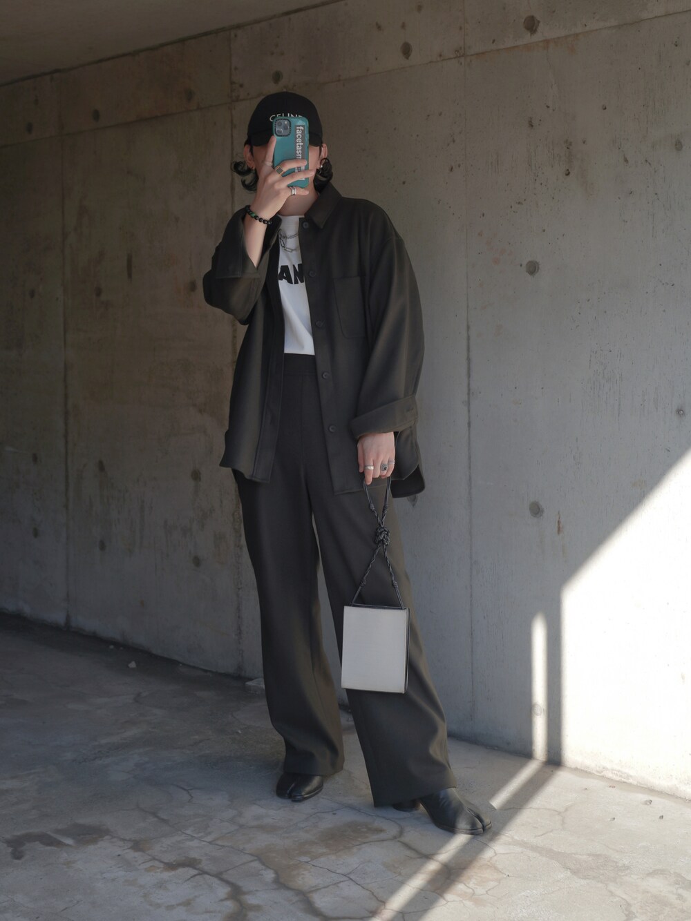 グリーン系のパンツ、ブラック系のブーツ、ホワイト系のショルダーバッグを着用したメンズの秋コーディネートの1枚目の写真