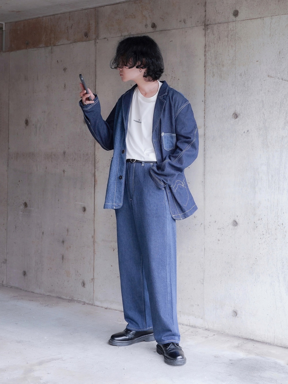 ブルー系のデニムパンツ、ブラック系のブーツ、その他のTシャツ/カットソーを着用したメンズの秋コーディネートの1枚目の写真