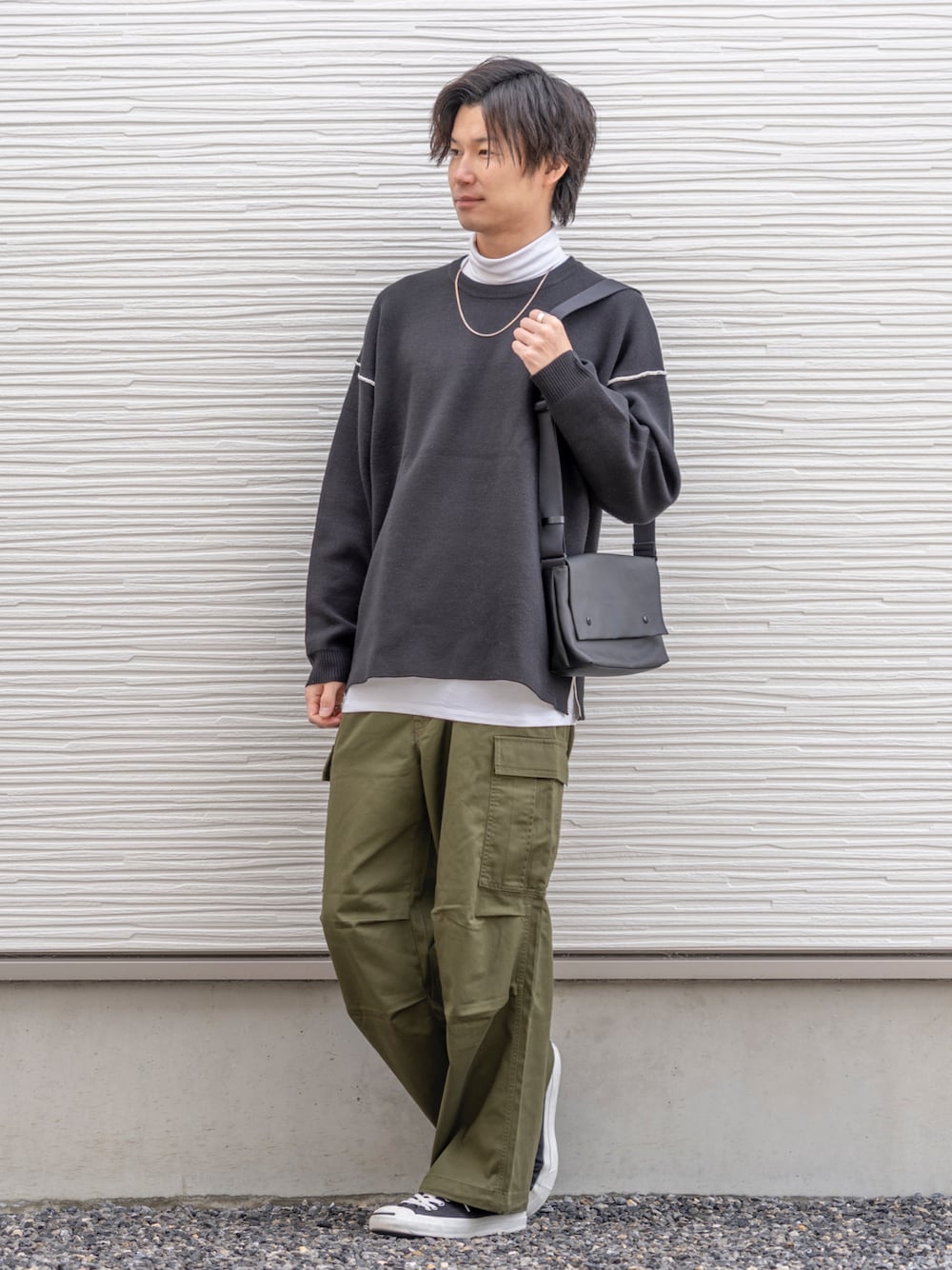 ブラック系のニット/セーター、ホワイト系のTシャツ/カットソー、グリーン系のカーゴパンツを着用したメンズの春コーディネートの1枚目の写真