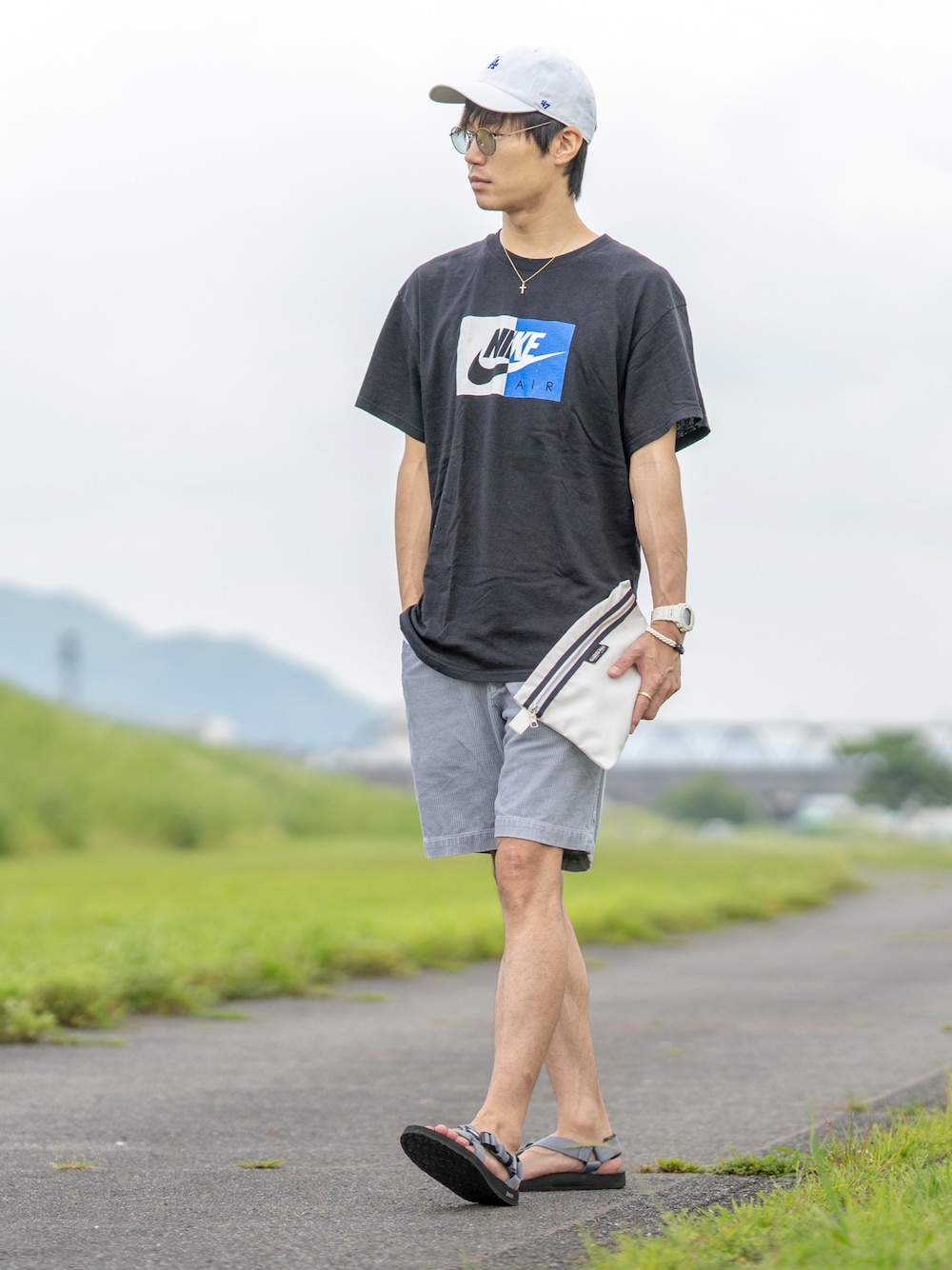 ブラック系のTシャツ/カットソー、ホワイト系のクラッチバッグ、ブルー系のその他パンツを着用したメンズの夏コーディネートの1枚目の写真