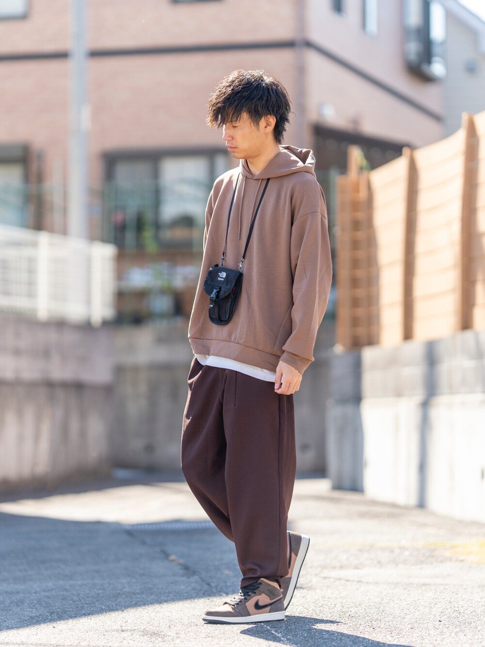 オレンジ系のパーカー、ブラック系のショルダーバッグ、ホワイト系のTシャツ/カットソーを着用したメンズの秋コーディネートの1枚目の写真