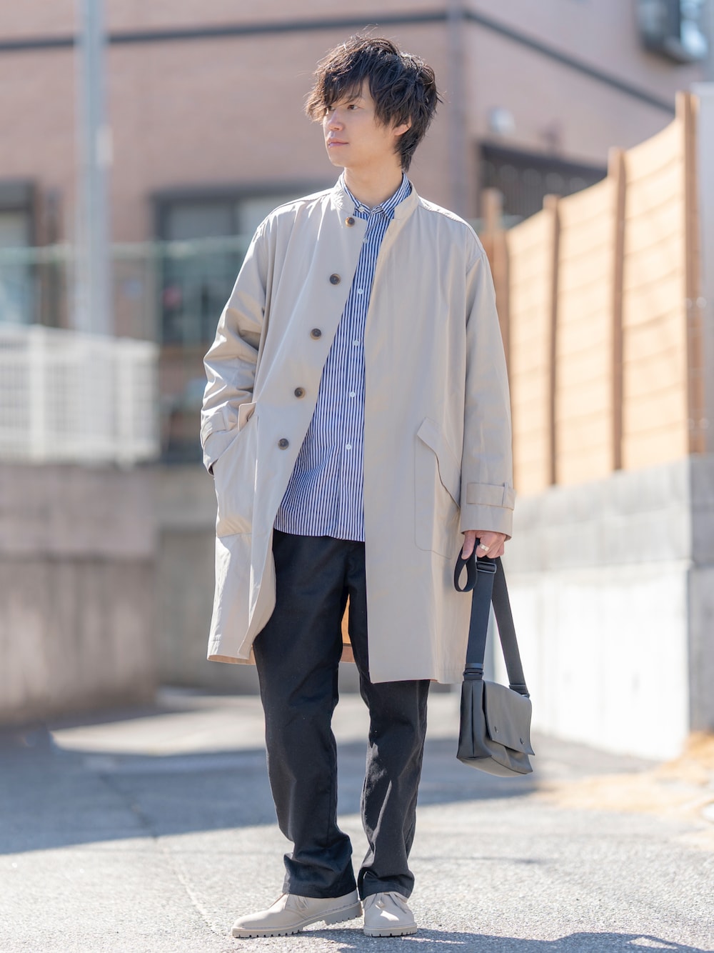 ベージュ系のステンカラーコート、ブルー系のシャツ/ブラウス、ブラック系のチノパンツを着用したメンズの春コーディネートの1枚目の写真