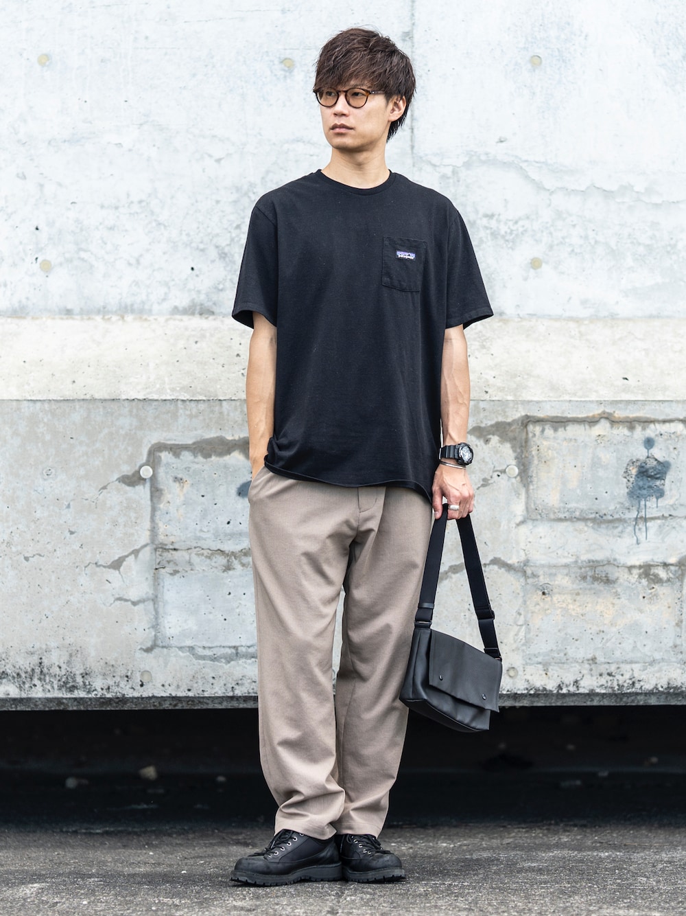 ブラック系のTシャツ/カットソー、ベージュ系のスラックス、ブラック系のショルダーバッグを着用したメンズの秋コーディネートの1枚目の写真
