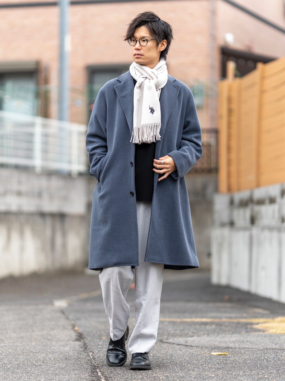 ブルー系のチェスターコート、ブラック系のニット/セーター、ブラック系のシューズを着用したメンズの冬コーディネートの1枚目の写真