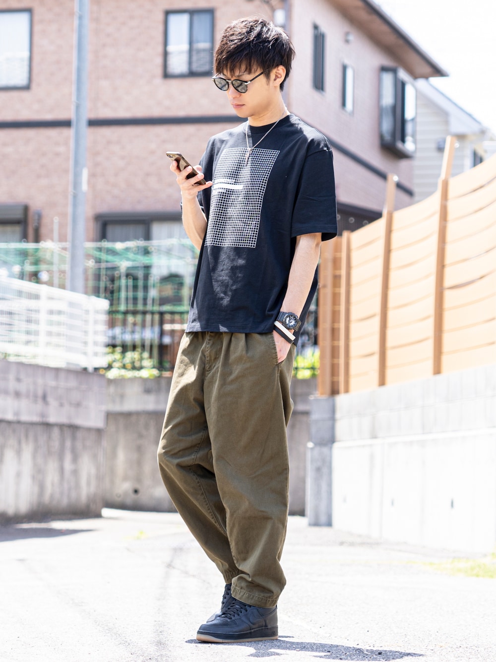 ブラック系のTシャツ/カットソー、グリーン系のチノパンツ、ブラック系のスニーカーを着用したメンズの夏コーディネートの1枚目の写真