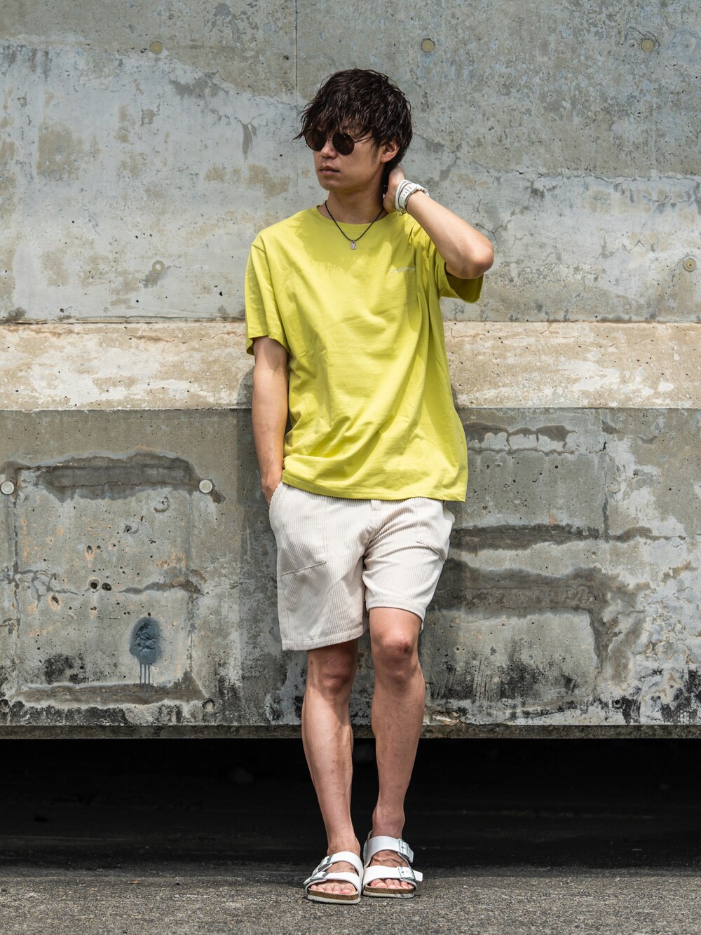 グリーン系のTシャツ/カットソー、ベージュ系のパンツ、ホワイト系のサンダルを着用したメンズの夏コーディネートの1枚目の写真
