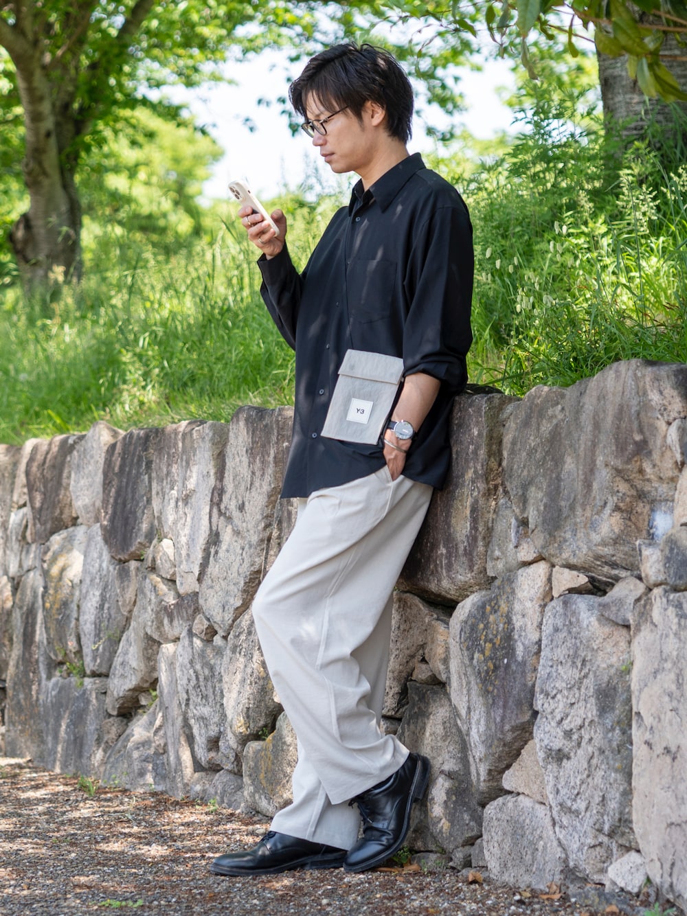 ブラック系のシャツ/ブラウス、ホワイト系のスラックス、ブラウン系のショルダーバッグを着用したメンズの春コーディネートの1枚目の写真