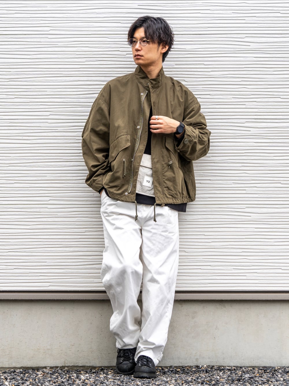 グリーン系のモッズコート、ブラック系のTシャツ/カットソー、ホワイト系のチノパンツを着用したメンズの春コーディネートの1枚目の写真