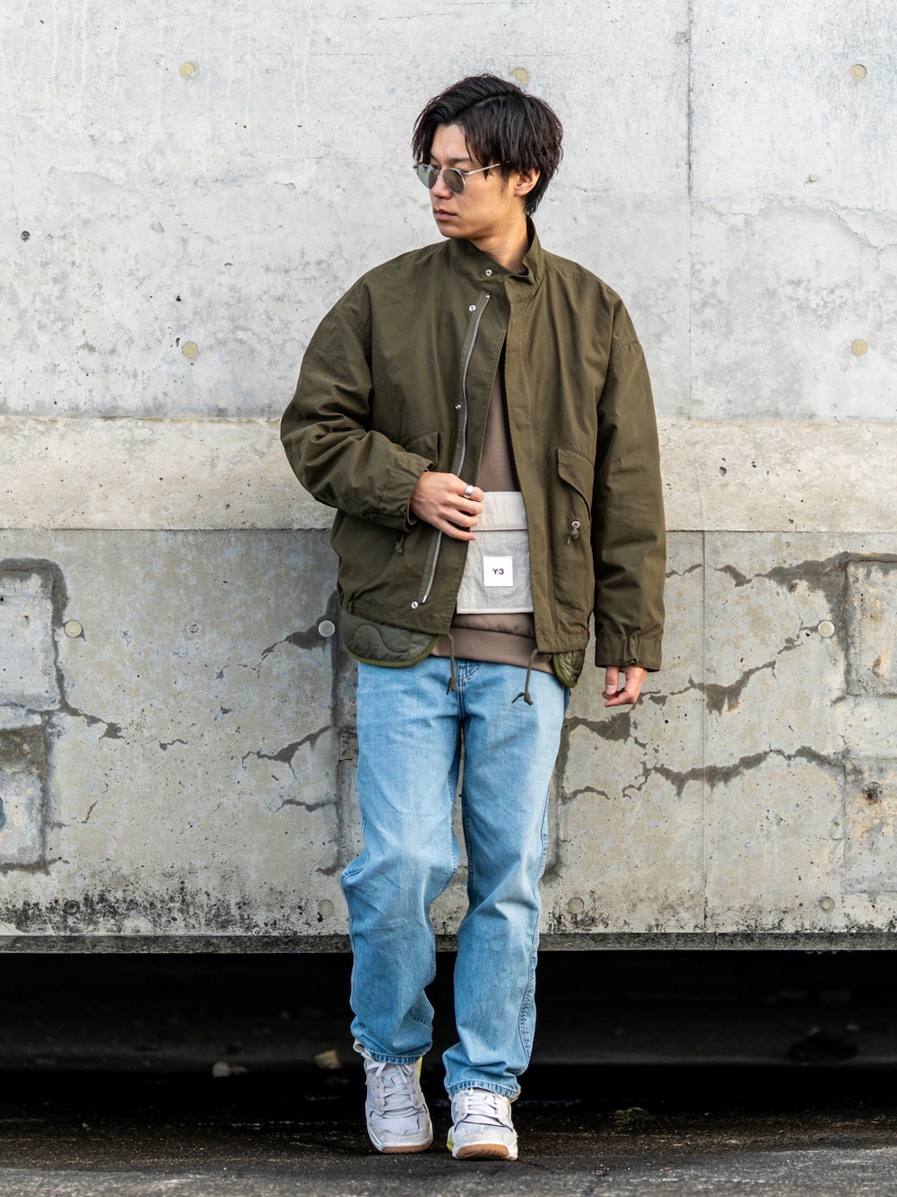 グリーン系のモッズコート、ベージュ系のスウェット、ブルー系のデニムパンツを着用したメンズの冬コーディネートの1枚目の写真