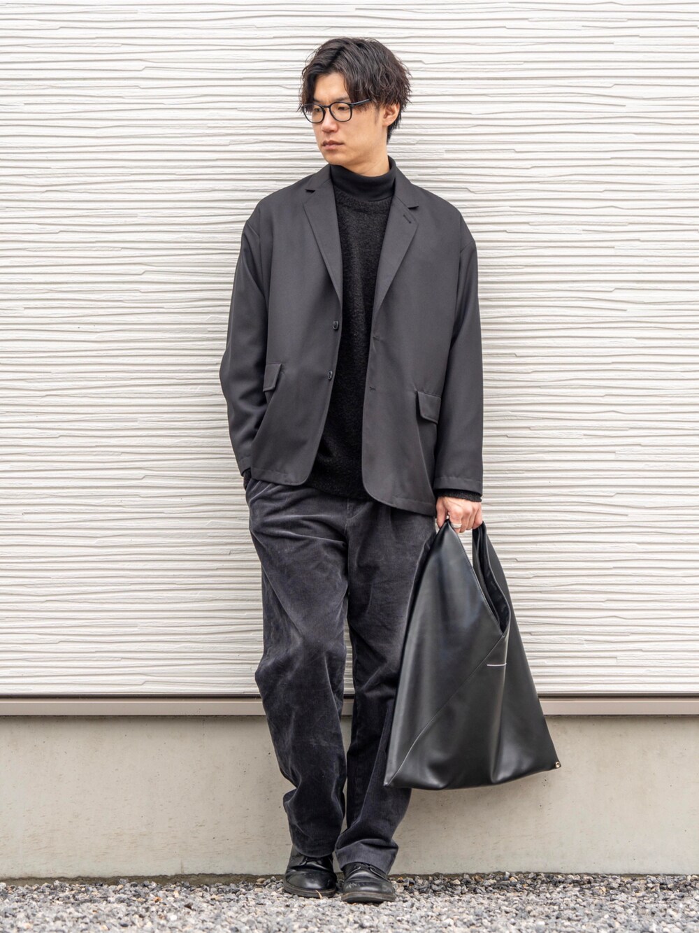 ブラック系のテーラードジャケット、グレー系のパンツ、ブラック系のトートバッグを着用したメンズの冬コーディネートの1枚目の写真