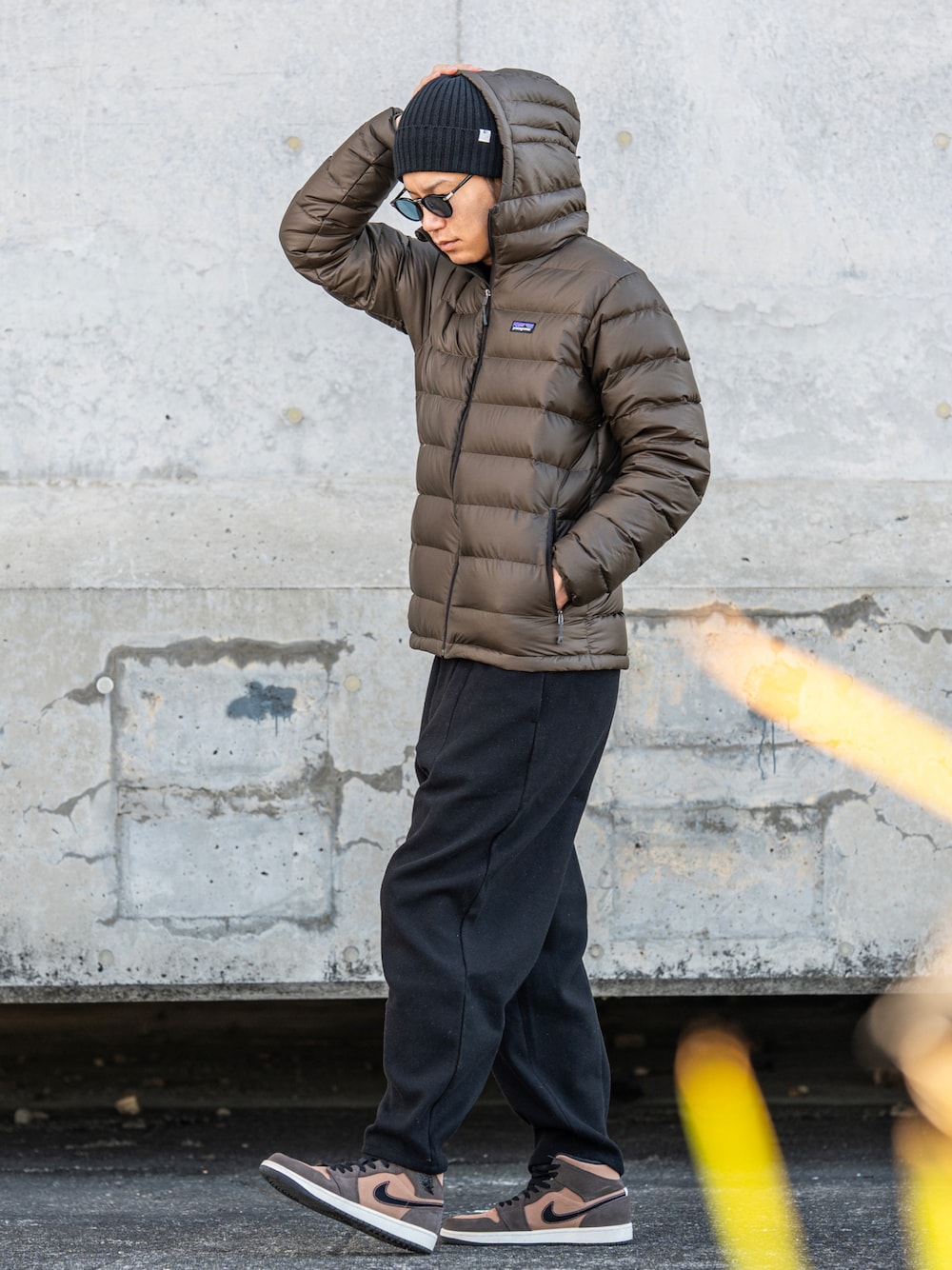 ブラウン系のダウンジャケット/コート、グレー系のパンツ、ブラウン系のスニーカーを着用したメンズの冬コーディネートの1枚目の写真