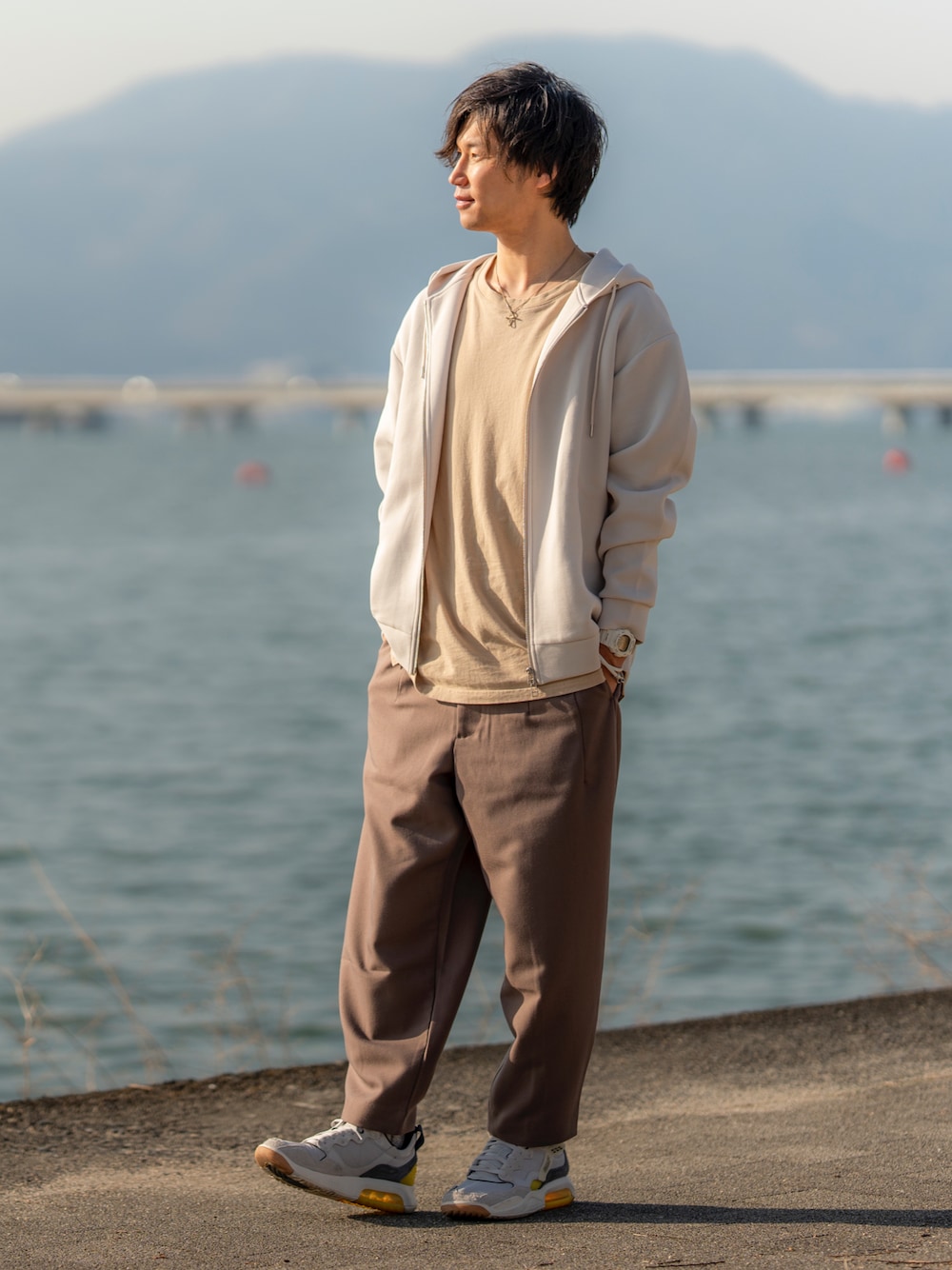 グレー系のパーカー、ベージュ系のTシャツ/カットソー、ブラウン系のパンツを着用したメンズの春コーディネートの1枚目の写真