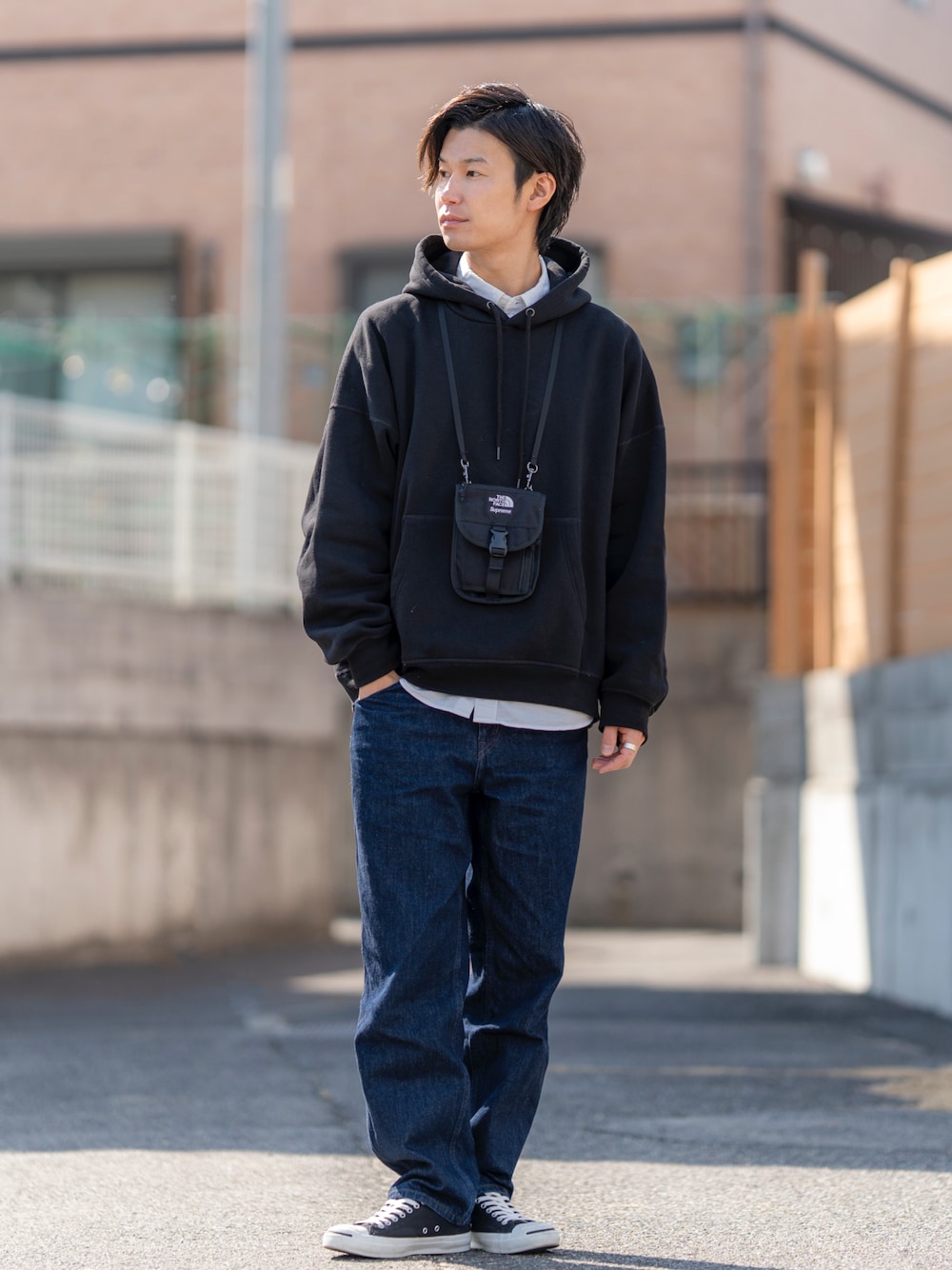 ブラック系のパーカー、ホワイト系のトップス、ブルー系のデニムパンツを着用したメンズの春コーディネートの1枚目の写真