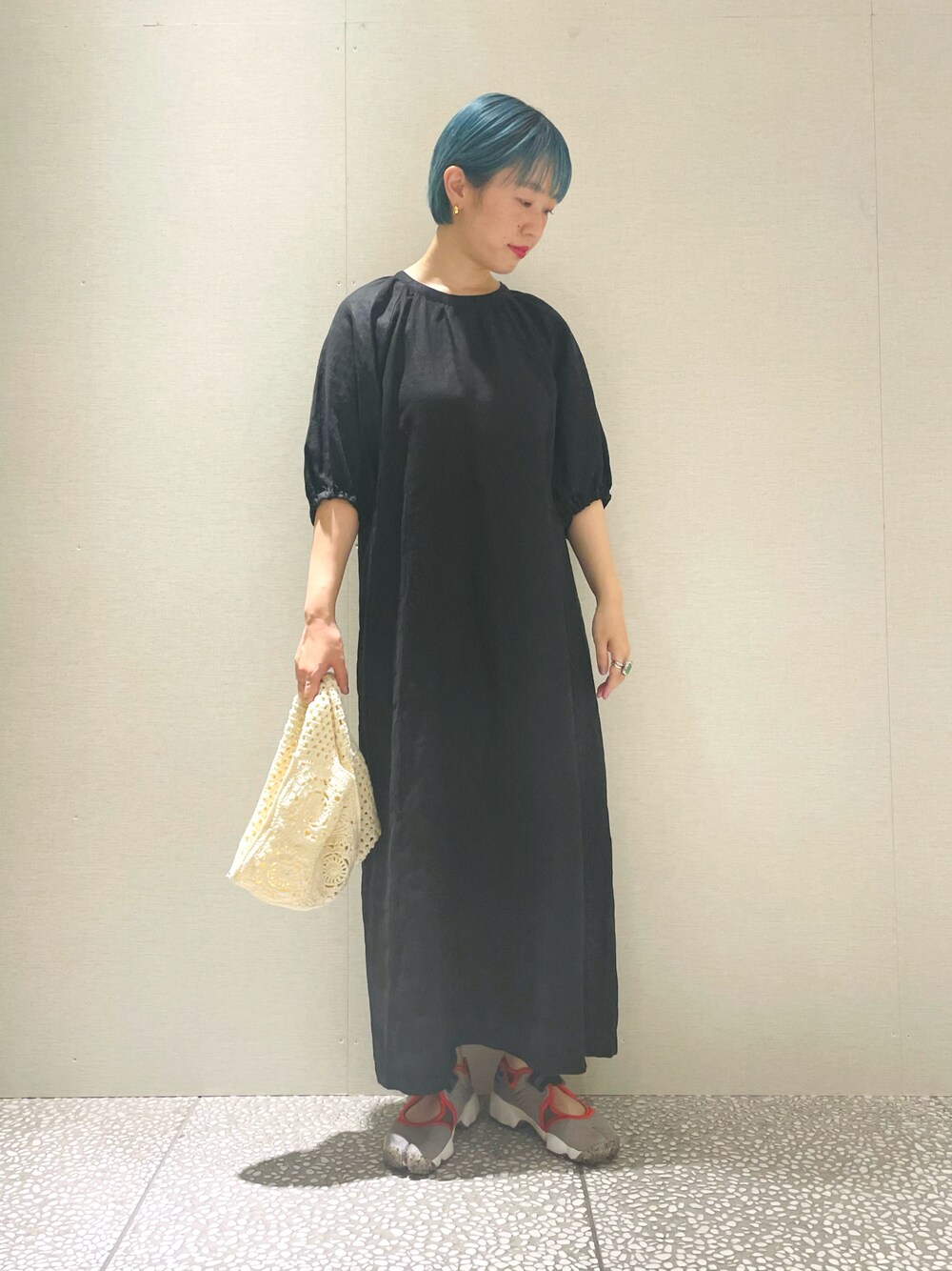 ブラック系のワンピース、ホワイト系のショルダーバッグ、グレー系のスニーカーを着用したレディースの春コーディネートの1枚目の写真