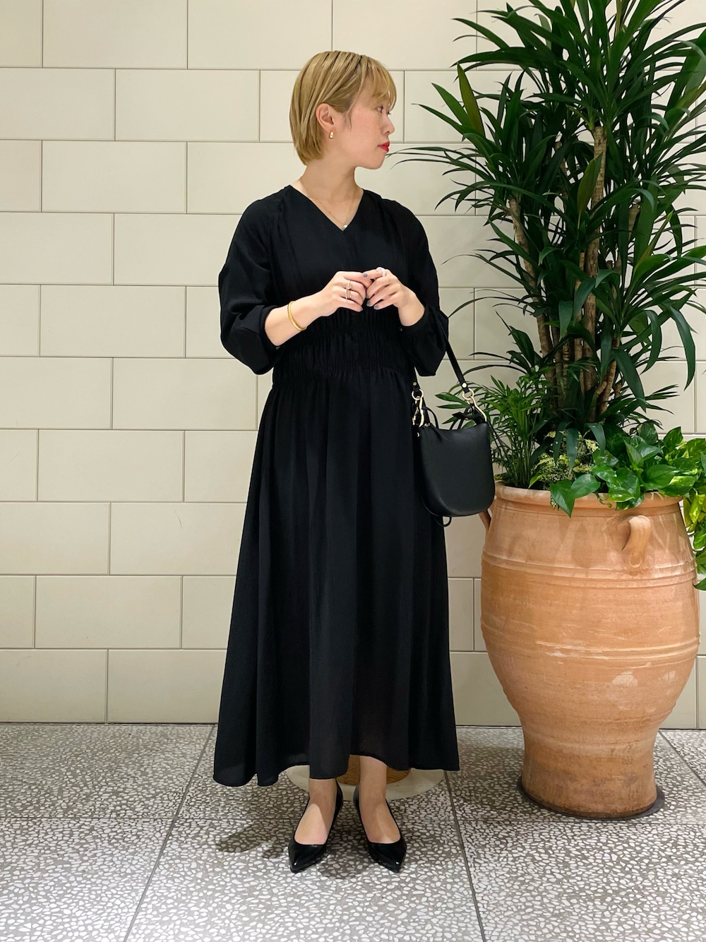 ブラック系のショルダーバッグ、ブラック系のワンピース、ブラック系のパンプスを着用したレディースの春コーディネートの1枚目の写真
