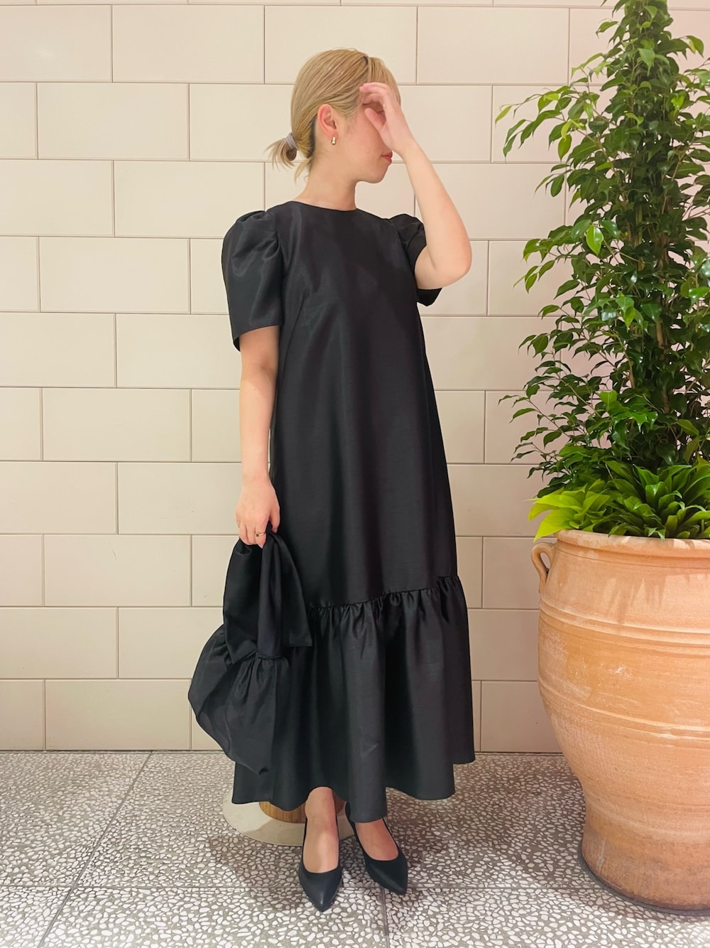 ブラック系のパンプス、ブラック系のドレス、ブラック系のハンドバッグを着用したレディースの春コーディネートの1枚目の写真
