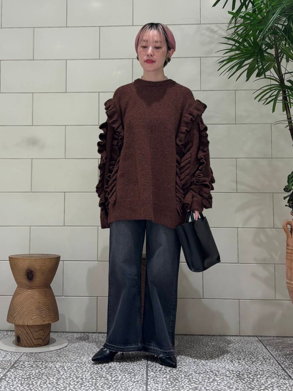 ブラック系のデニムパンツ、ブラック系のトートバッグ、ブラウン系のブーツを着用したレディースの冬コーディネートの1枚目の写真