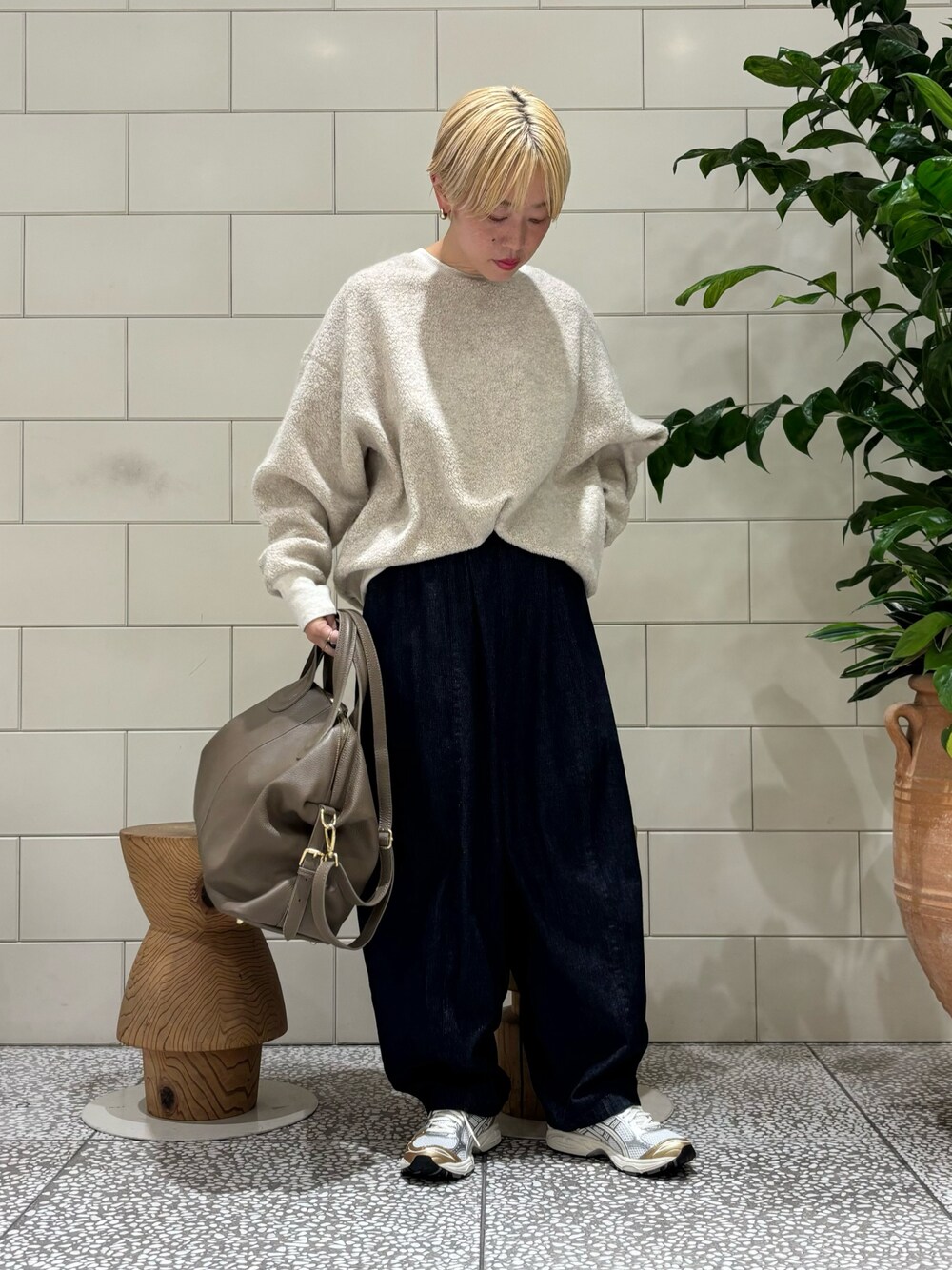 ベージュ系のボストンバッグ、ベージュ系のTシャツ/カットソー、ホワイト系のスニーカーを着用したレディースの秋コーディネートの1枚目の写真