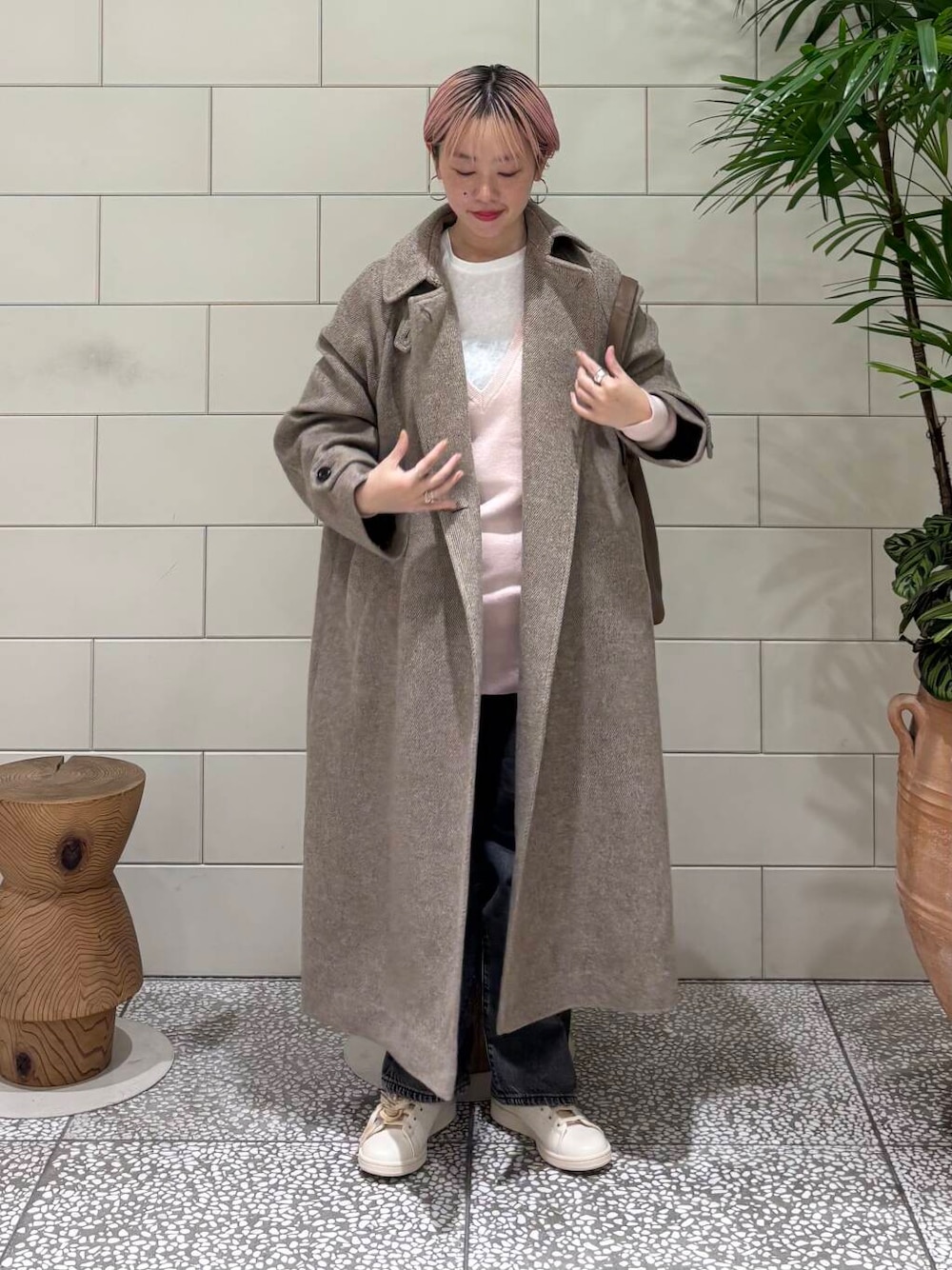 ブラック系のデニムパンツ、ブラウン系のステンカラーコート、ホワイト系のTシャツ/カットソーを着用したレディースの冬コーディネートの1枚目の写真