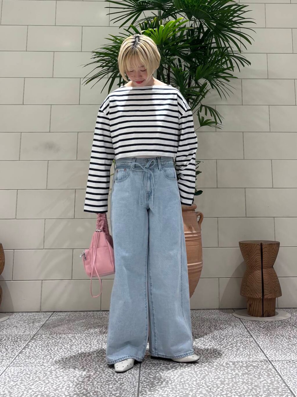 レッド系のショルダーバッグ、ホワイト系のパンプス、ブルー系のTシャツ/カットソーを着用したレディースの冬コーディネートの1枚目の写真
