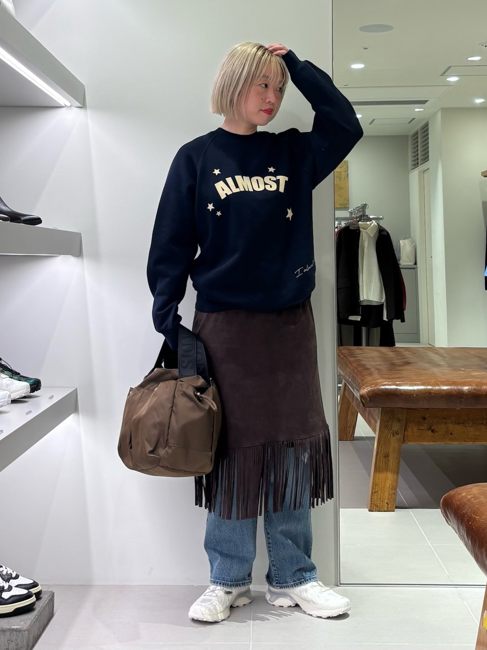 ブラウン系のスカート、ブルー系のデニムパンツ、ブラウン系のショルダーバッグを着用したレディースの秋コーディネートの1枚目の写真