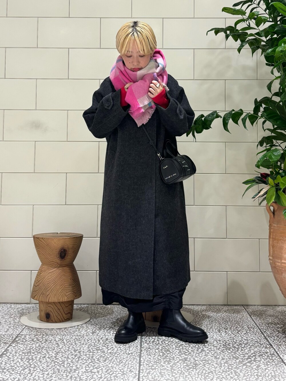 ブラック系のステンカラーコート、ブラック系のスカート、レッド系のTシャツ/カットソーを着用したレディースの秋コーディネートの1枚目の写真