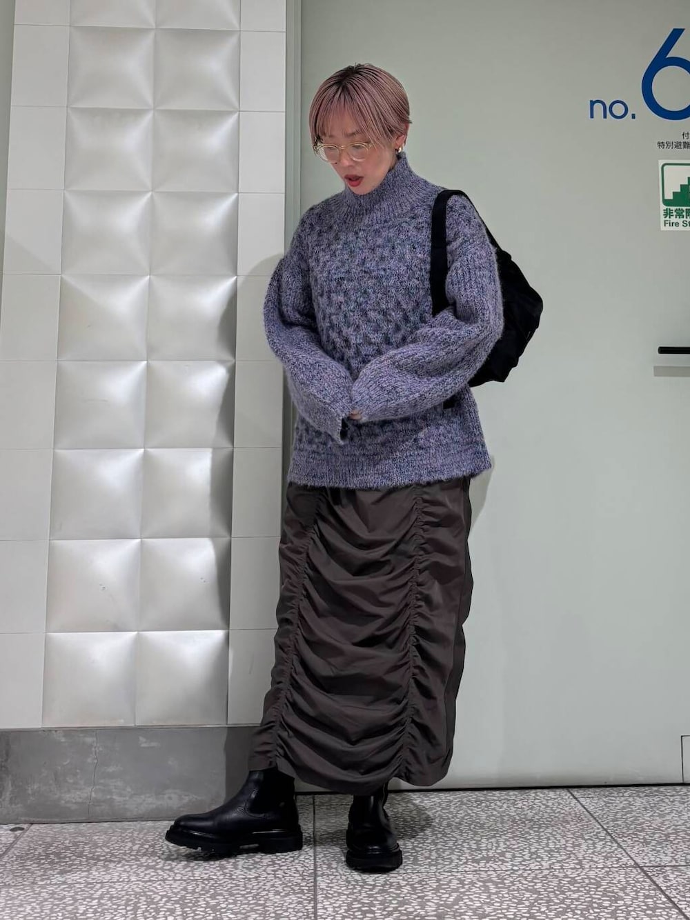 グレー系のスカート、ブルー系のニット/セーター、ブラック系のショルダーバッグを着用したレディースの秋コーディネートの1枚目の写真