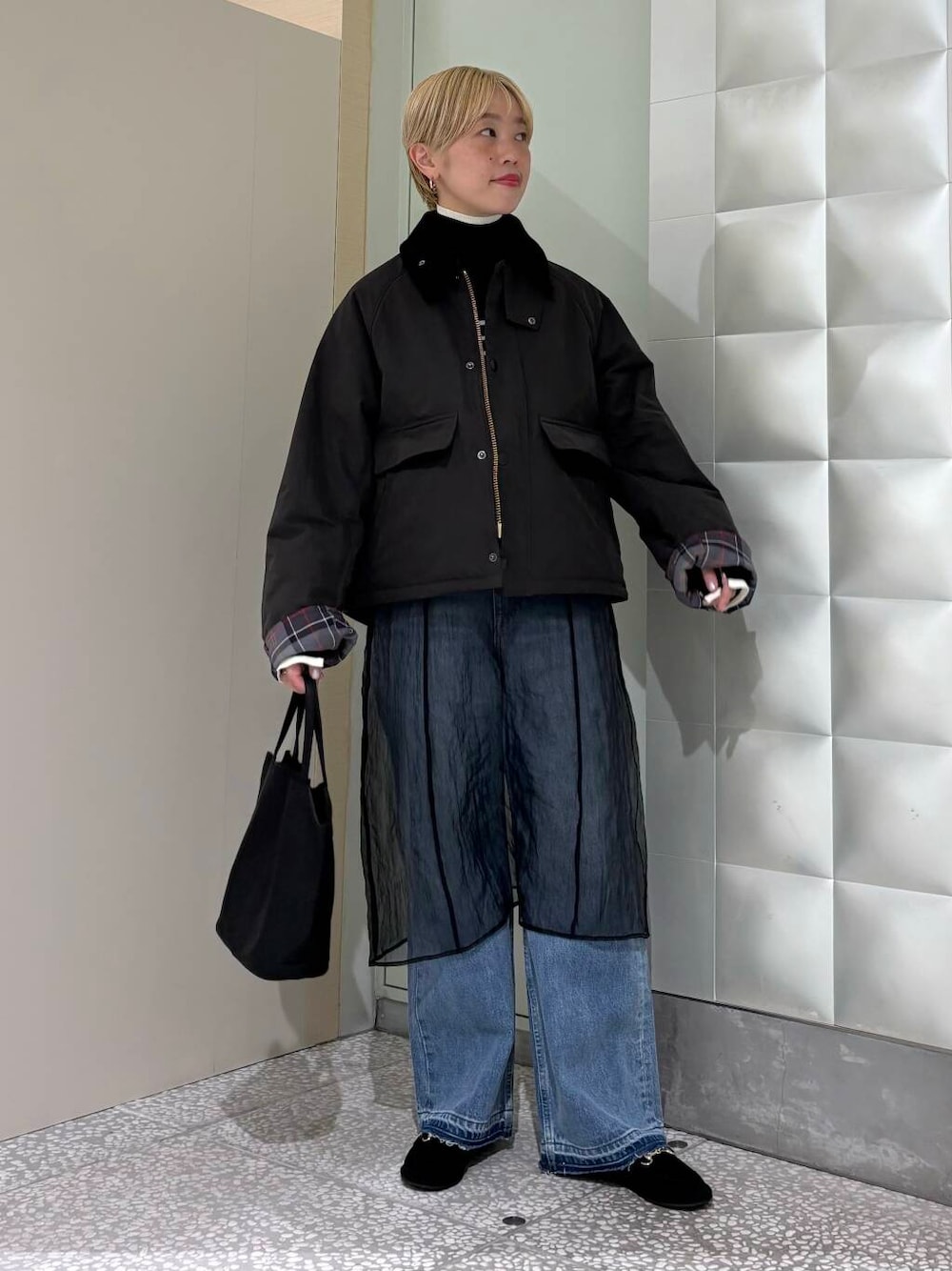 ブラック系のニット/セーター、ブルー系のデニムパンツ、ブラック系のその他アウターを着用したレディースの秋コーディネートの1枚目の写真