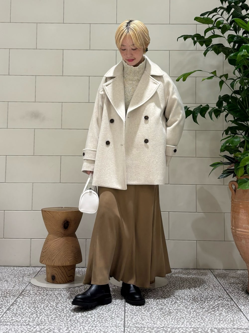 イエロー系のスカート、ホワイト系のボストンバッグ、ホワイト系のニット/セーターを着用したレディースの秋コーディネートの1枚目の写真