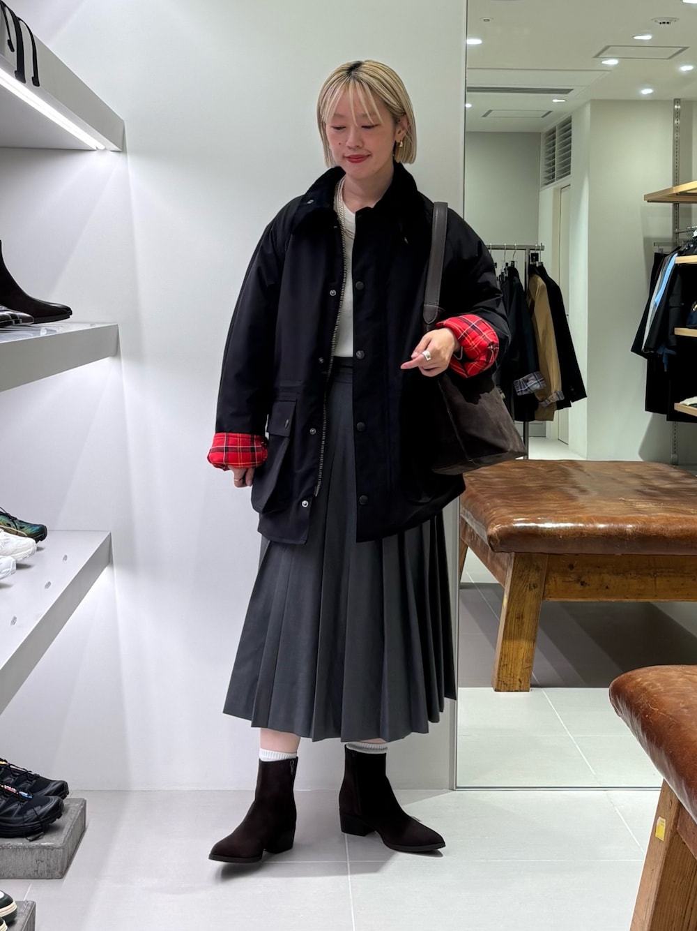 グリーン系のスカート、ブラウン系のトートバッグ、ブラック系のその他アウターを着用したレディースの秋コーディネートの1枚目の写真