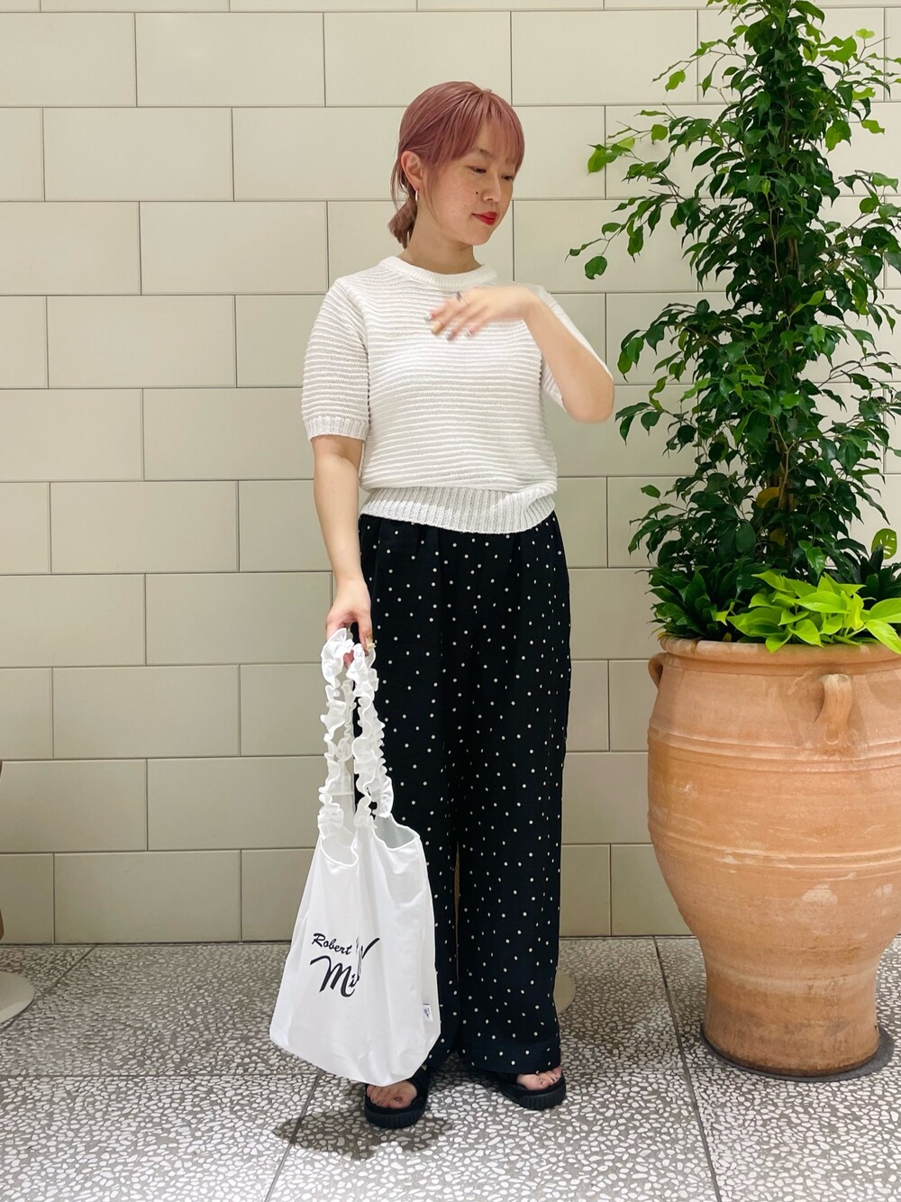 ホワイト系のニット/セーター、ブラック系のその他パンツ、ホワイト系のトートバッグを着用したレディースの春コーディネートの1枚目の写真