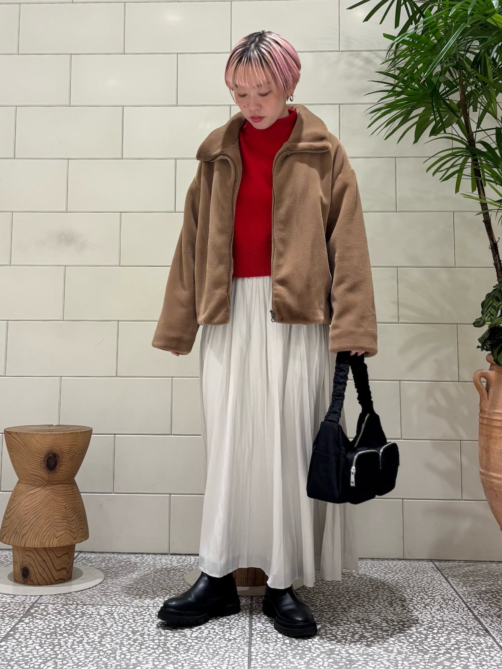 イエロー系のその他アウター、ホワイト系のスカート、レッド系のニット/セーターを着用したレディースの冬コーディネートの1枚目の写真