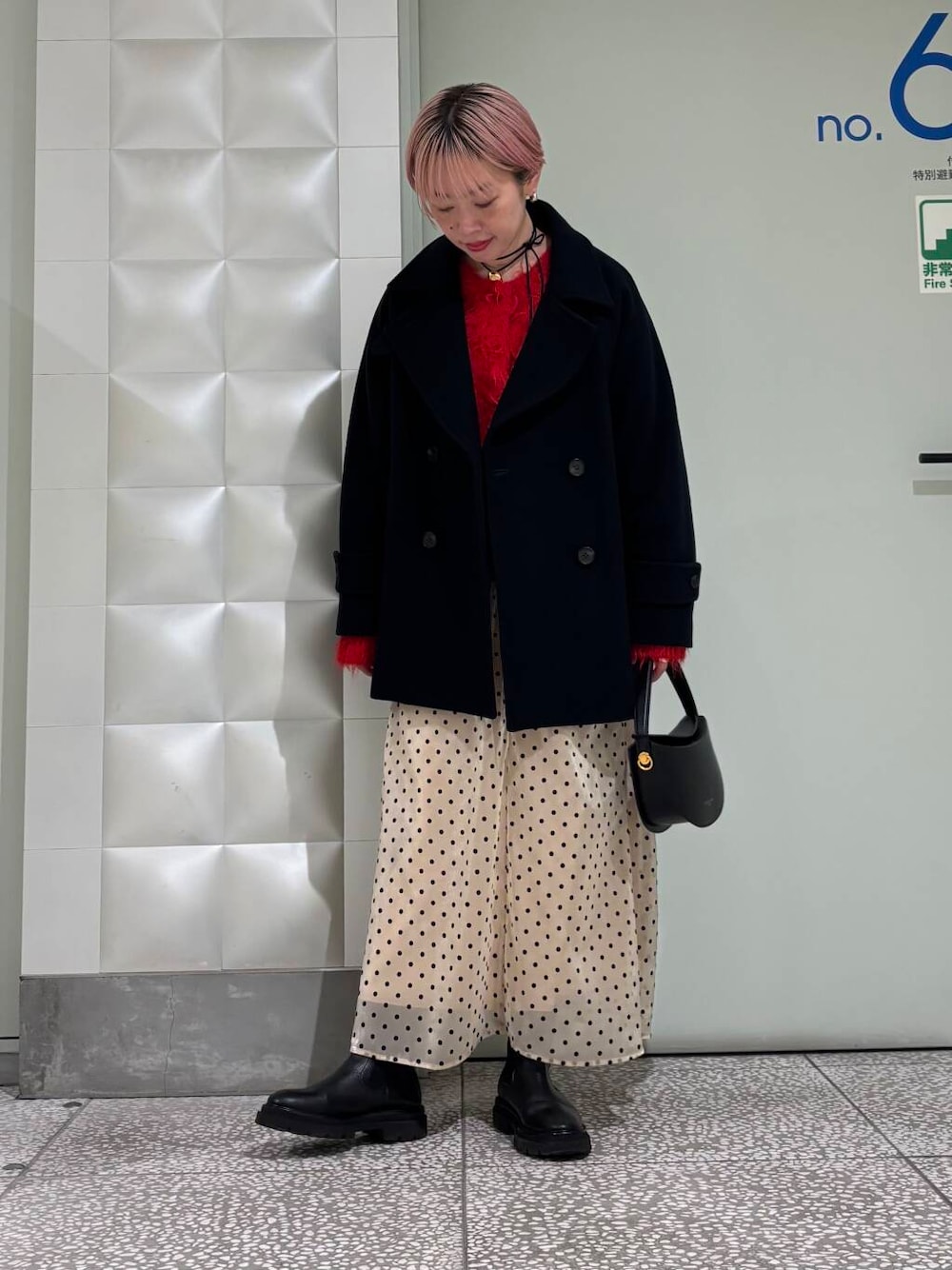 ブルー系のピーコート、レッド系のカーディガン/ボレロ、ベージュ系のスカートを着用したレディースの冬コーディネートの1枚目の写真