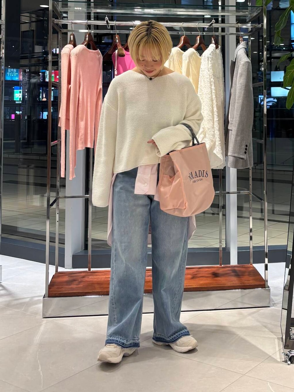 ブルー系のデニムパンツ、ピンク系のシャツ/ブラウス、ホワイト系のニット/セーターを着用したレディースの冬コーディネートの1枚目の写真