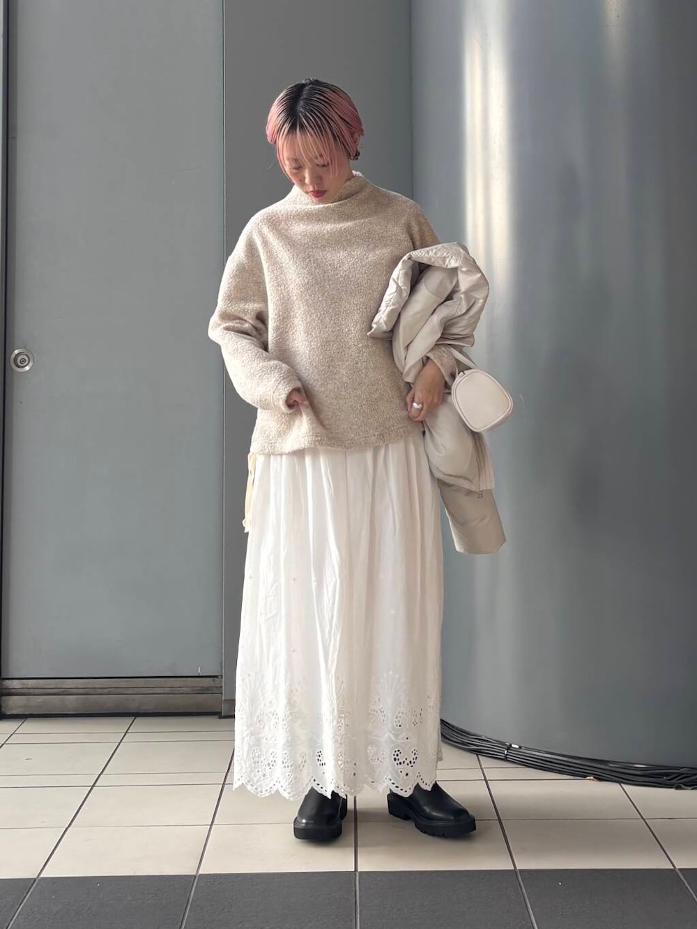 ホワイト系のボストンバッグ、ホワイト系のスカート、ホワイト系のダウンジャケット/コートを着用したレディースの冬コーディネートの1枚目の写真