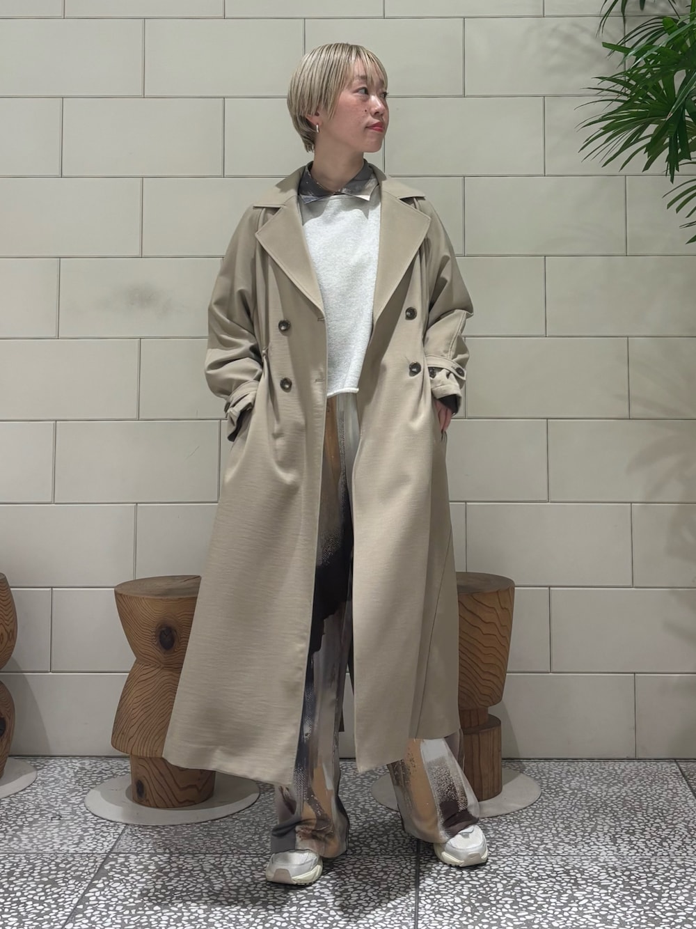 ベージュ系のトレンチコート、オレンジ系のシャツ/ブラウス、ベージュ系のスウェットを着用したレディースの冬コーディネートの1枚目の写真