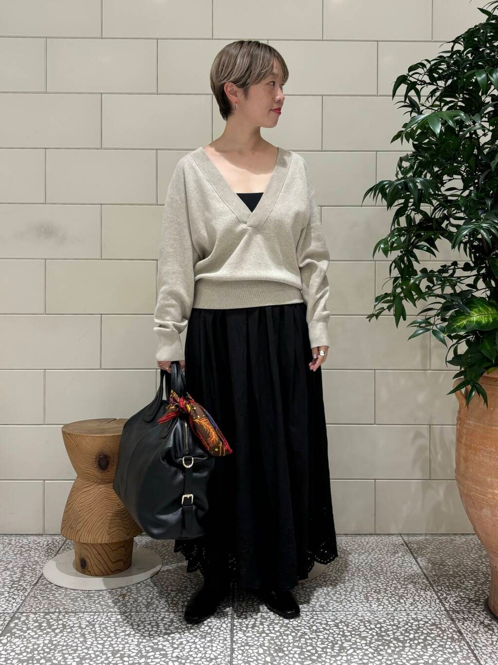 ベージュ系のニット/セーター、ブラック系のボストンバッグ、ブラック系のスカートを着用したレディースの秋コーディネートの1枚目の写真