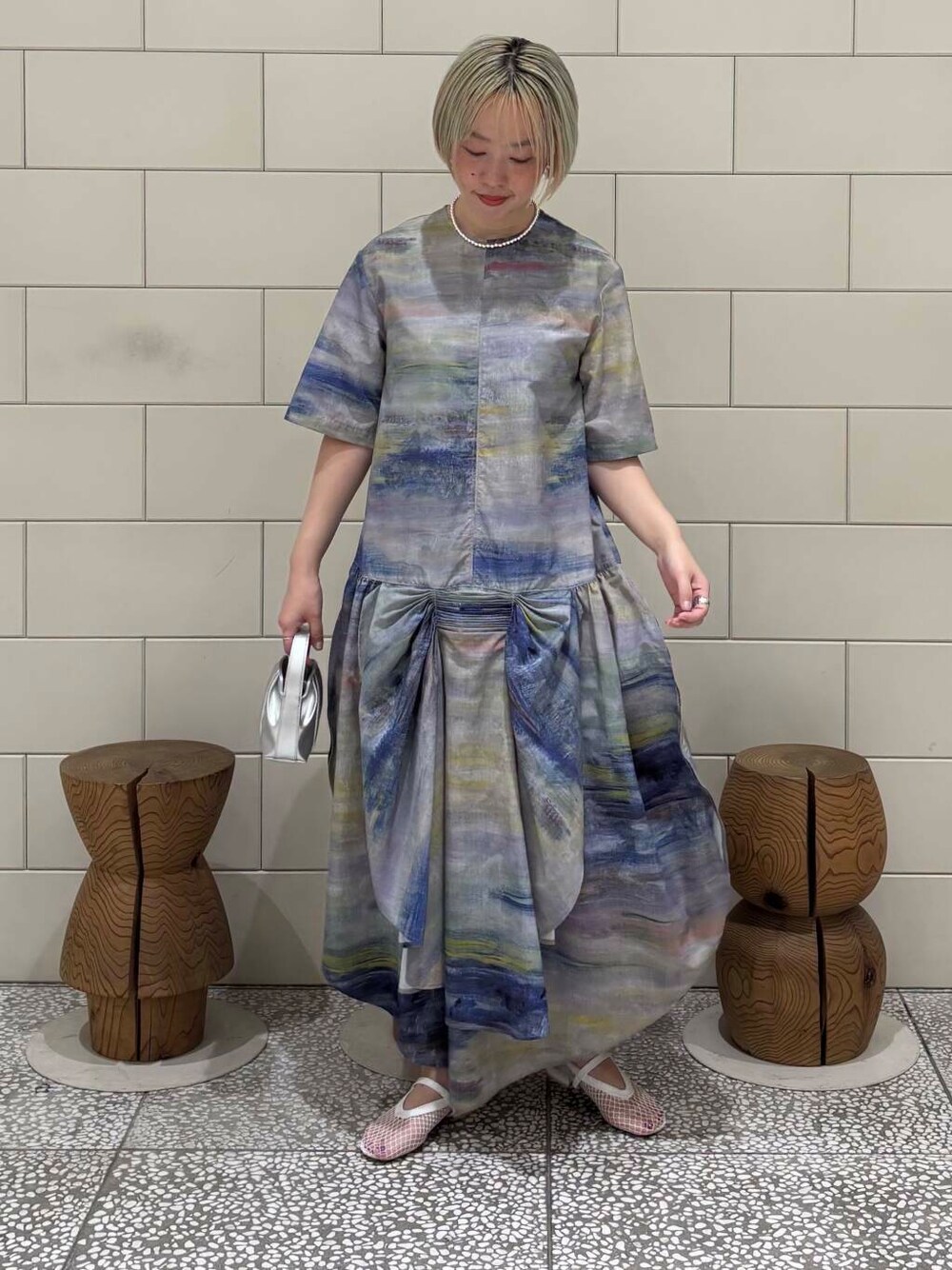 シルバー系のハンドバッグ、ホワイト系のパンプス、シルバー系のネックレスを着用したレディースの春コーディネートの1枚目の写真