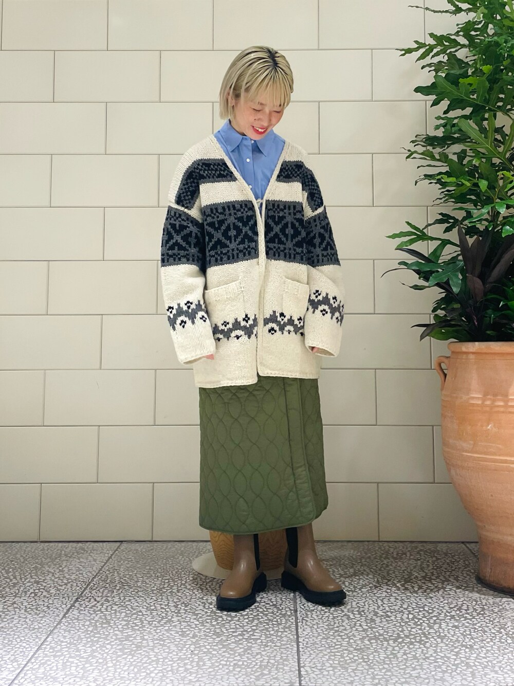 ホワイト系のカーディガン/ボレロ、ブルー系のシャツ/ブラウス、グリーン系のスカートを着用したレディースの秋コーディネートの1枚目の写真