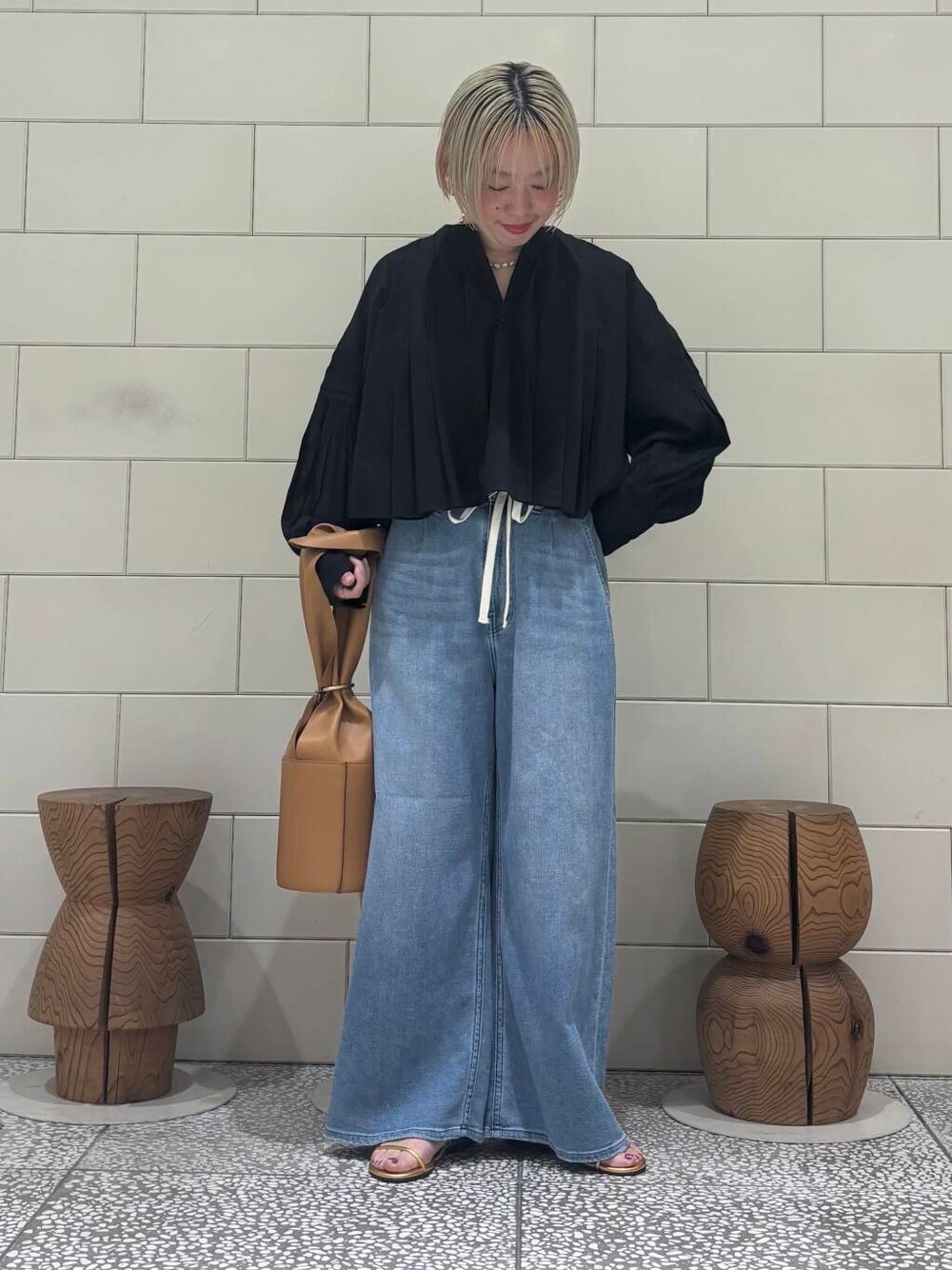 ブラック系のシャツ/ブラウス、ブルー系のデニムパンツ、ゴールド系のサンダルを着用したレディースの春コーディネートの1枚目の写真