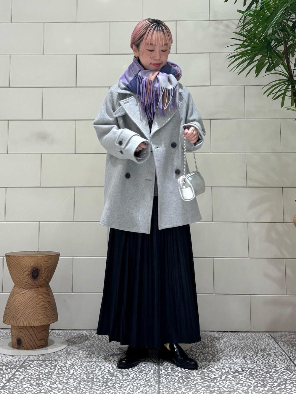 グレー系のニット/セーター、グレー系のピーコート、ブルー系のスカートを着用したレディースの冬コーディネートの1枚目の写真