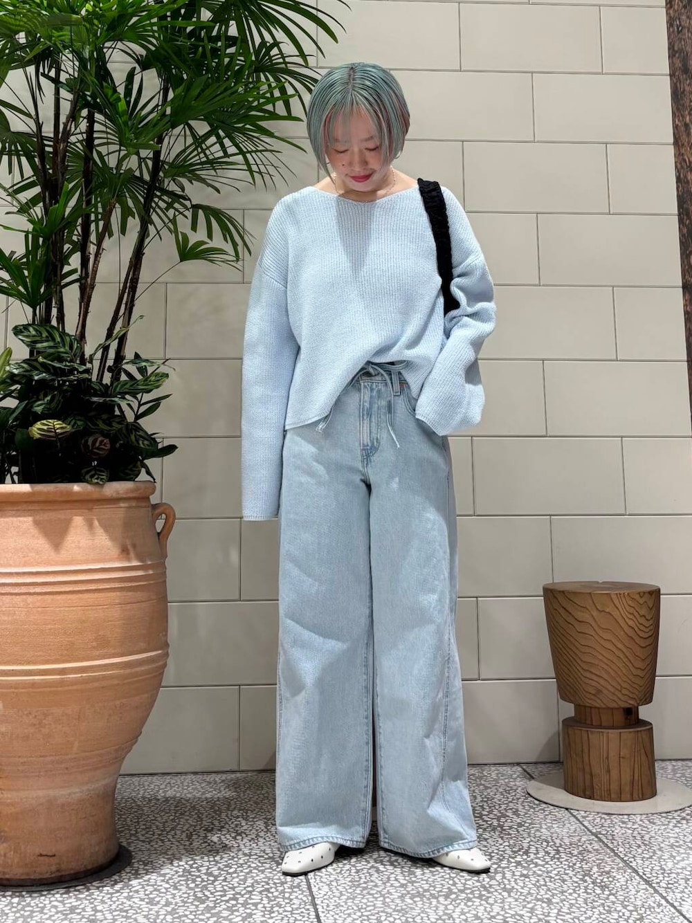 ブラック系のショルダーバッグ、ホワイト系のパンプス、ブルー系のニット/セーターを着用したレディースの春コーディネートの1枚目の写真
