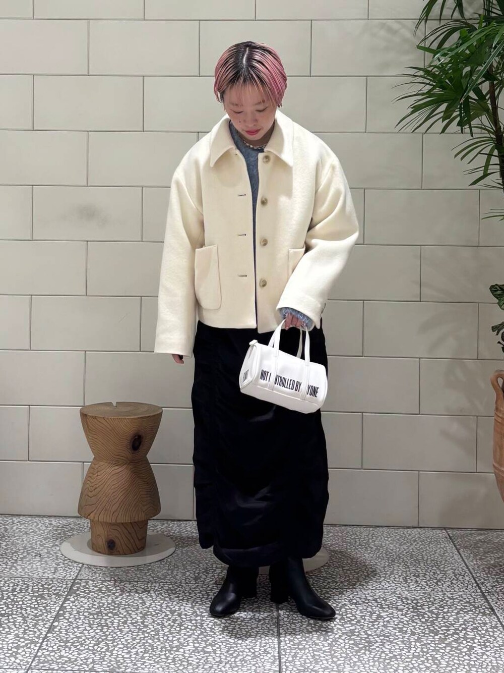 ブラック系のブーツ、ホワイト系のボストンバッグ、ブラック系のスカートを着用したレディースの冬コーディネートの1枚目の写真