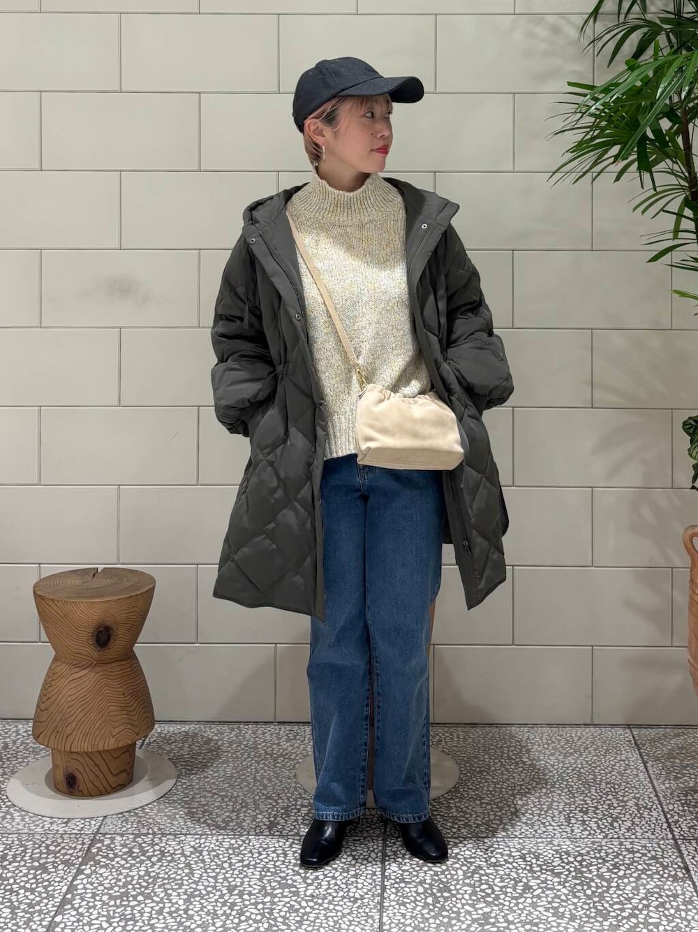 ブルー系のデニムパンツ、ベージュ系のショルダーバッグ、ホワイト系のニット/セーターを着用したレディースの冬コーディネートの1枚目の写真