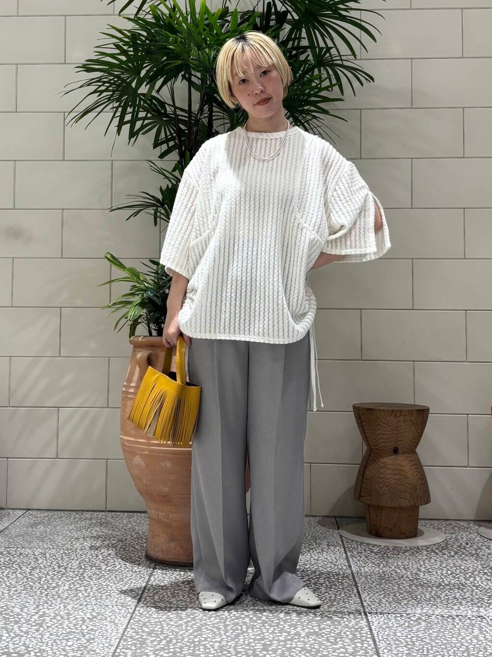 ホワイト系のパンプス、グレー系のその他パンツ、イエロー系のハンドバッグを着用したレディースの春コーディネートの1枚目の写真