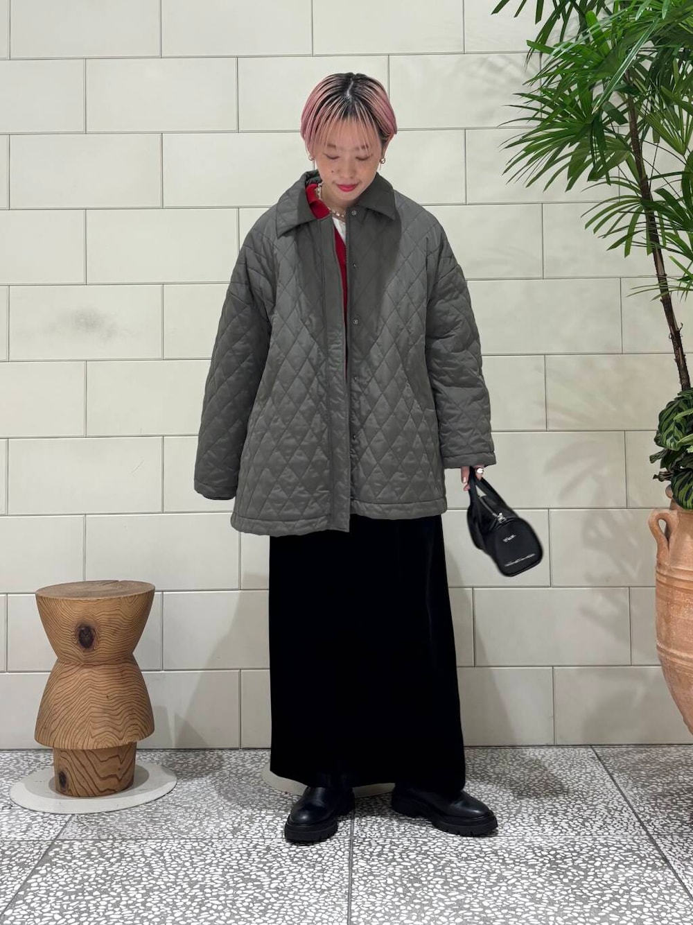 ブラック系のボストンバッグ、レッド系のニット/セーター、ブラック系のスカートを着用したレディースの冬コーディネートの1枚目の写真