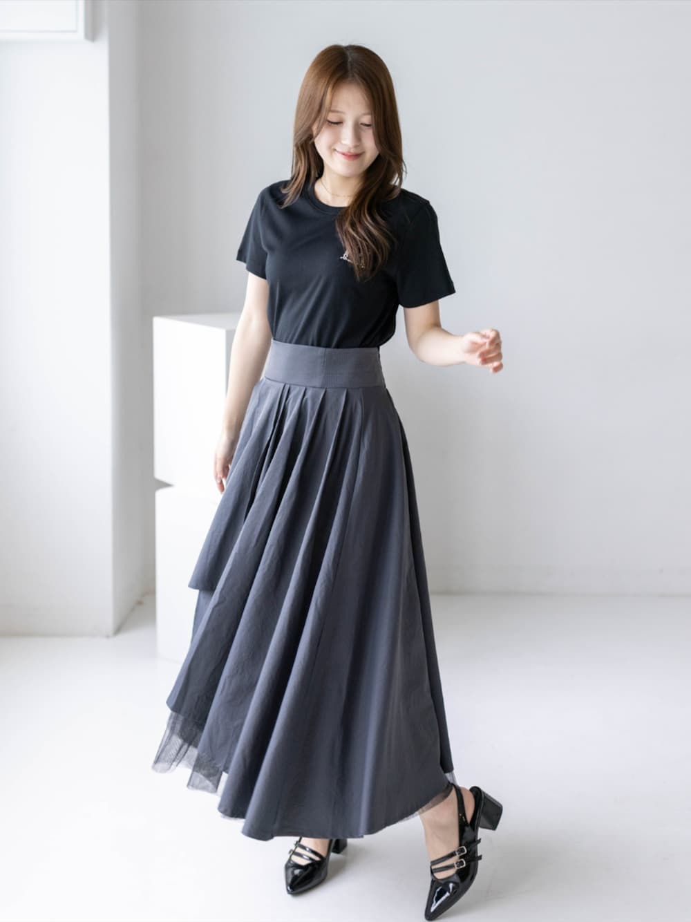 ブラック系のパンプス、グレー系のスカート、ブラック系のTシャツ/カットソーを着用したレディースの夏コーディネートの1枚目の写真
