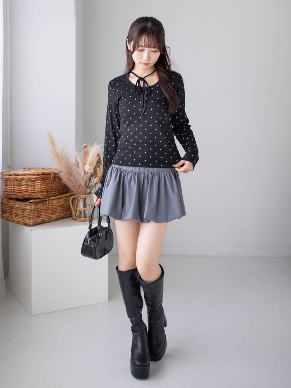 グレー系のスカート、ブラック系のブーツ、ブラック系のTシャツ/カットソーを着用したレディースの秋コーディネートの1枚目の写真